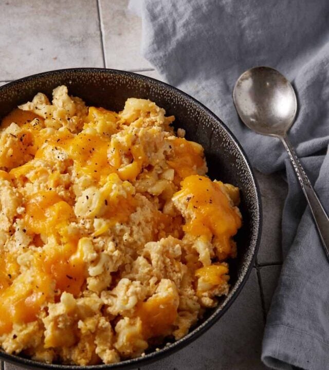 A bowl of crock pot mac n cheese in a bowl next to a spoon.