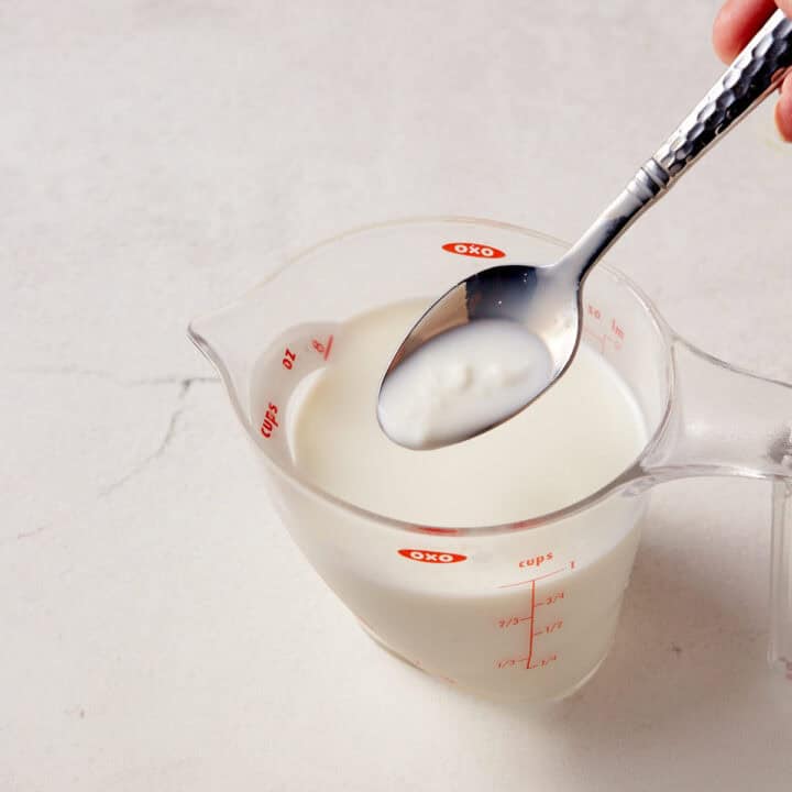 A teaspoon of buttermilk substitute over a measuring cup.