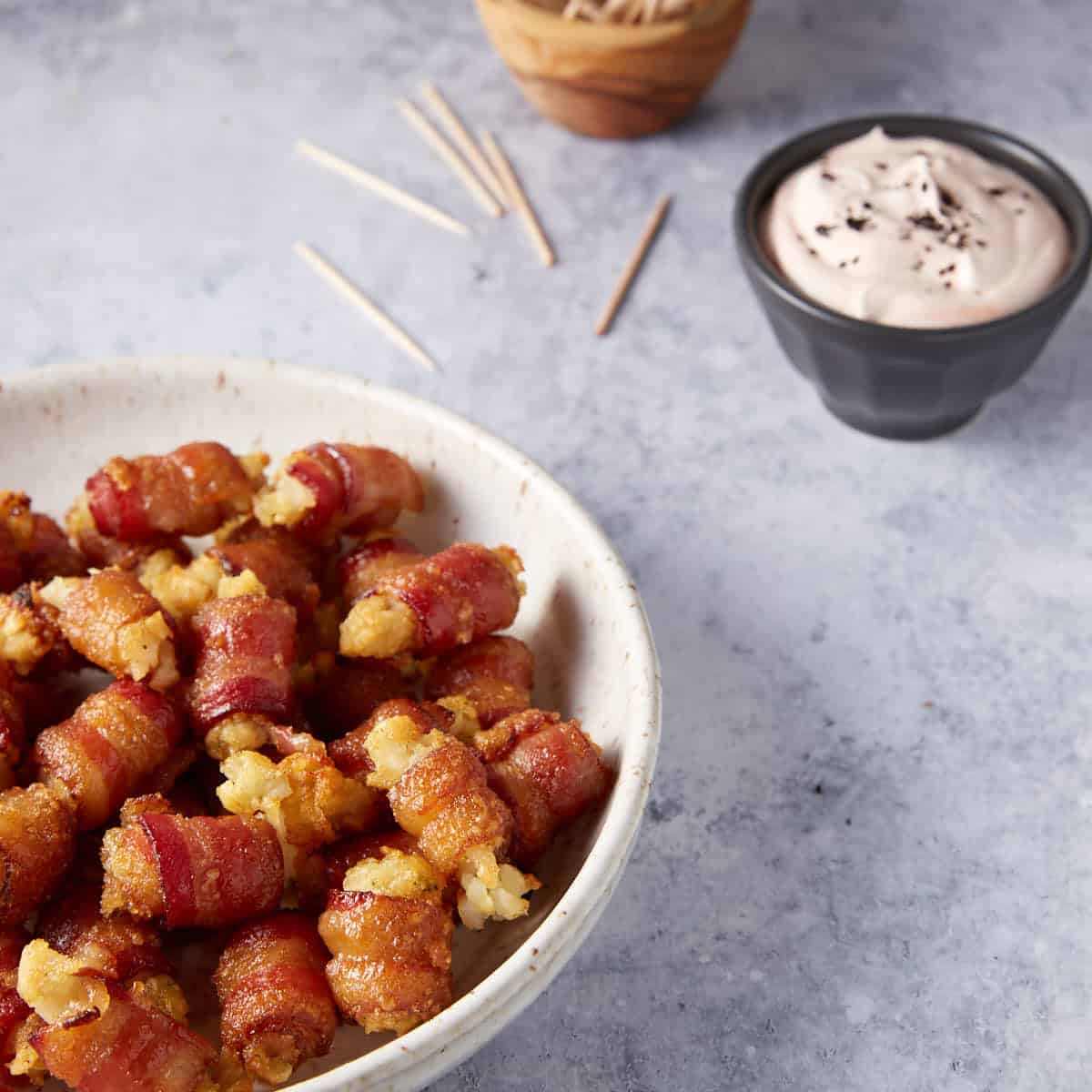 A serving bowl of tater tots wrapped in bacon.
