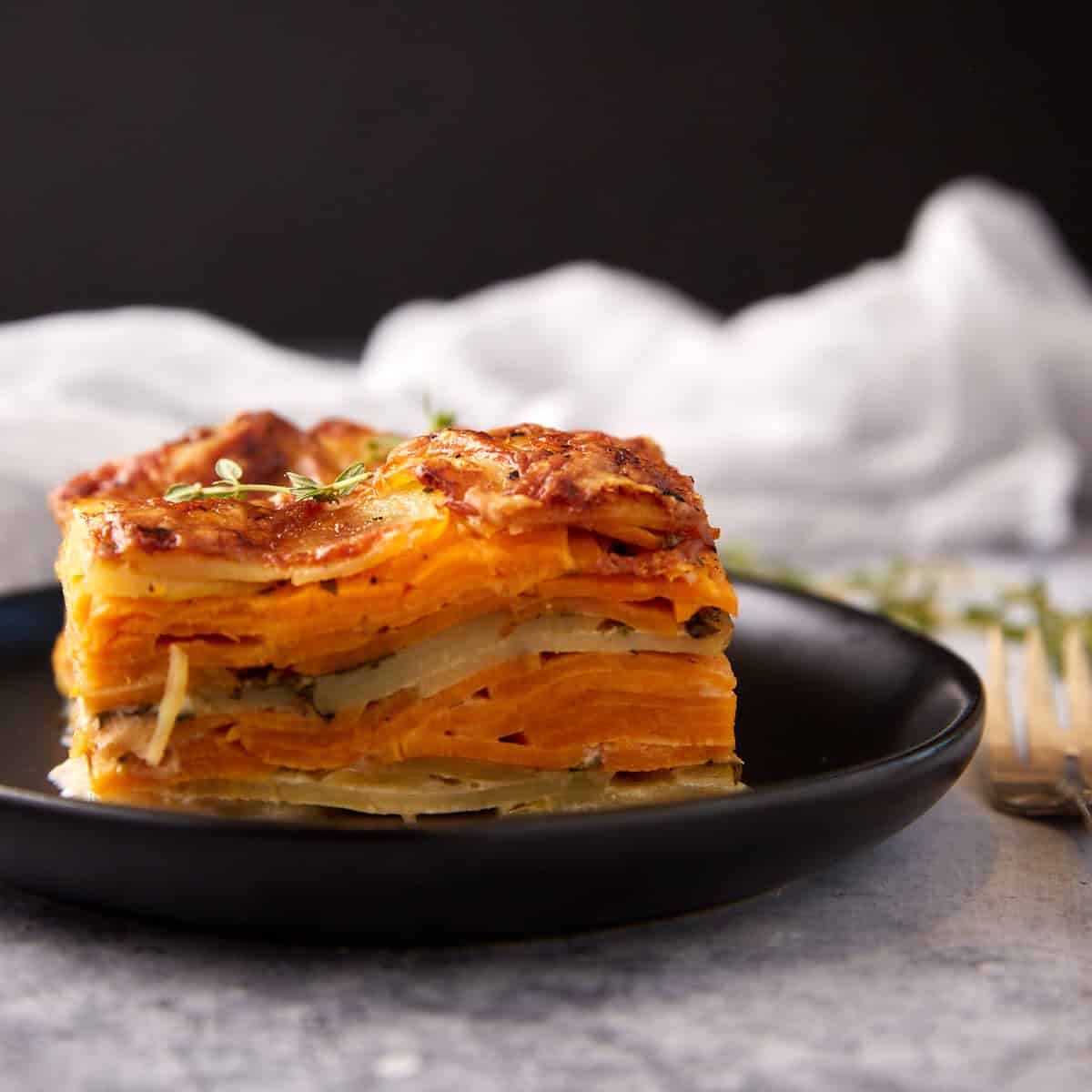 A square serving of scalloped sweet poatoes.