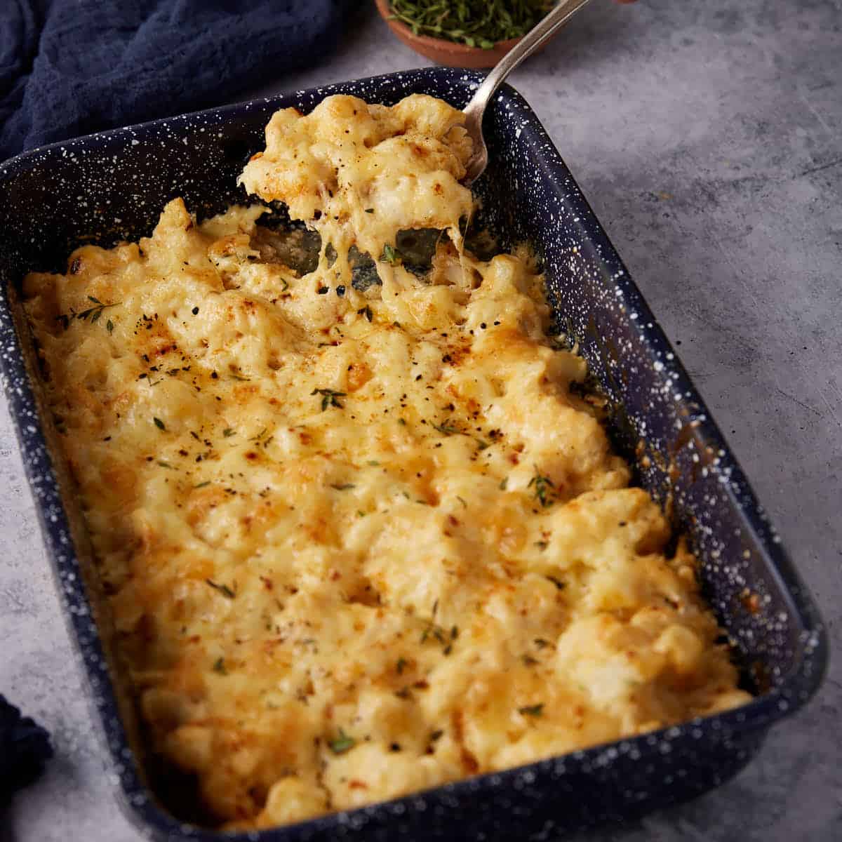 Cheesy cauliflower casserole with a serving spoon.