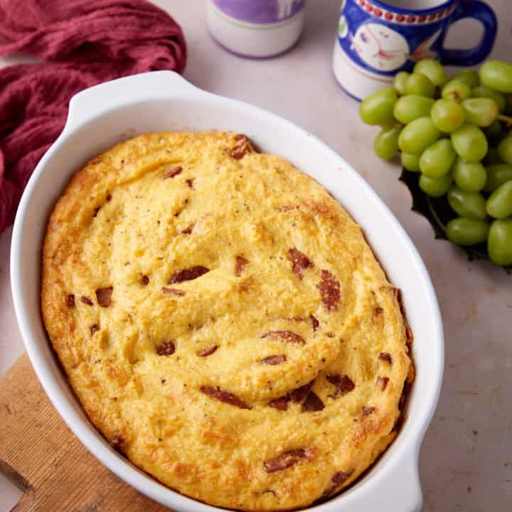 A sausage and grits casserole next to coffee mugs.