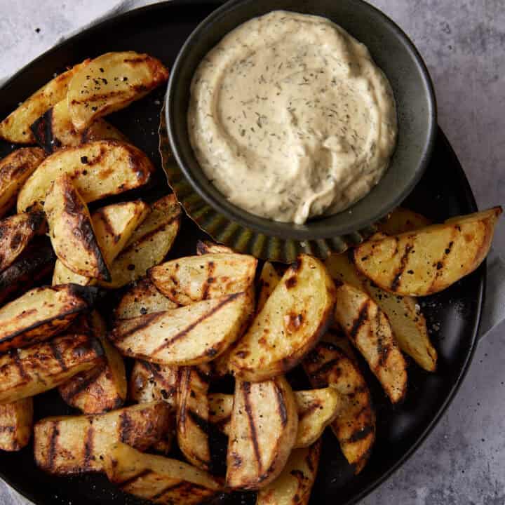Easy grilled potatoes on a platter next to a dipping sauce.