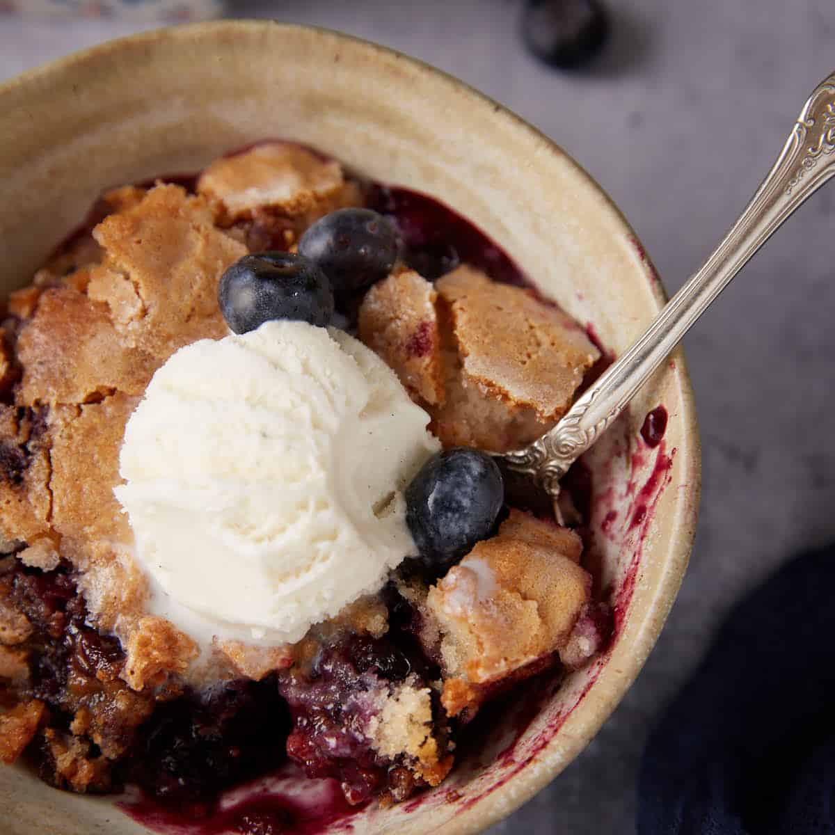 A bowl of self-saucing pudding topped with ice cream.