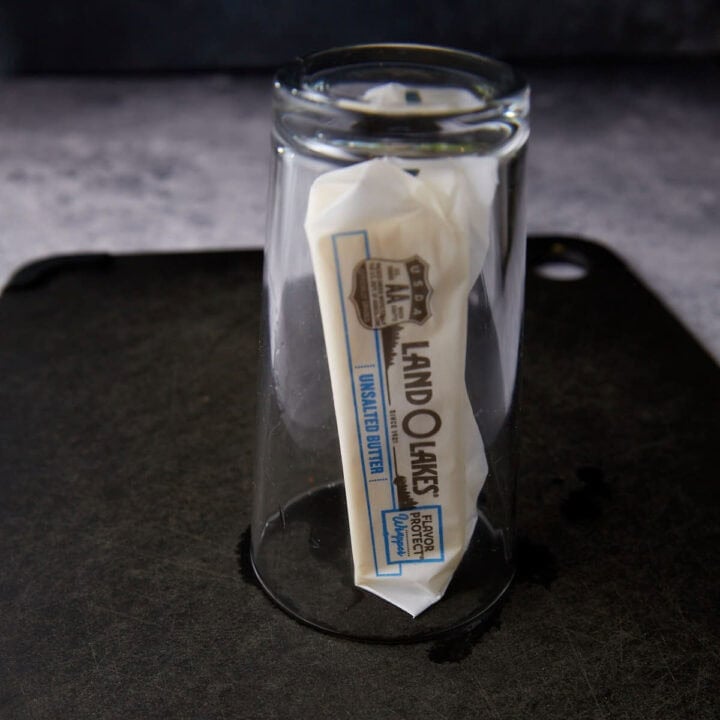 A stick of butter under a glass.