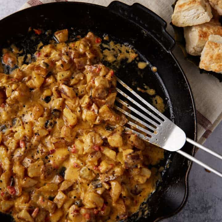 A skillet of crispy potatoes coated in pimento cheese.