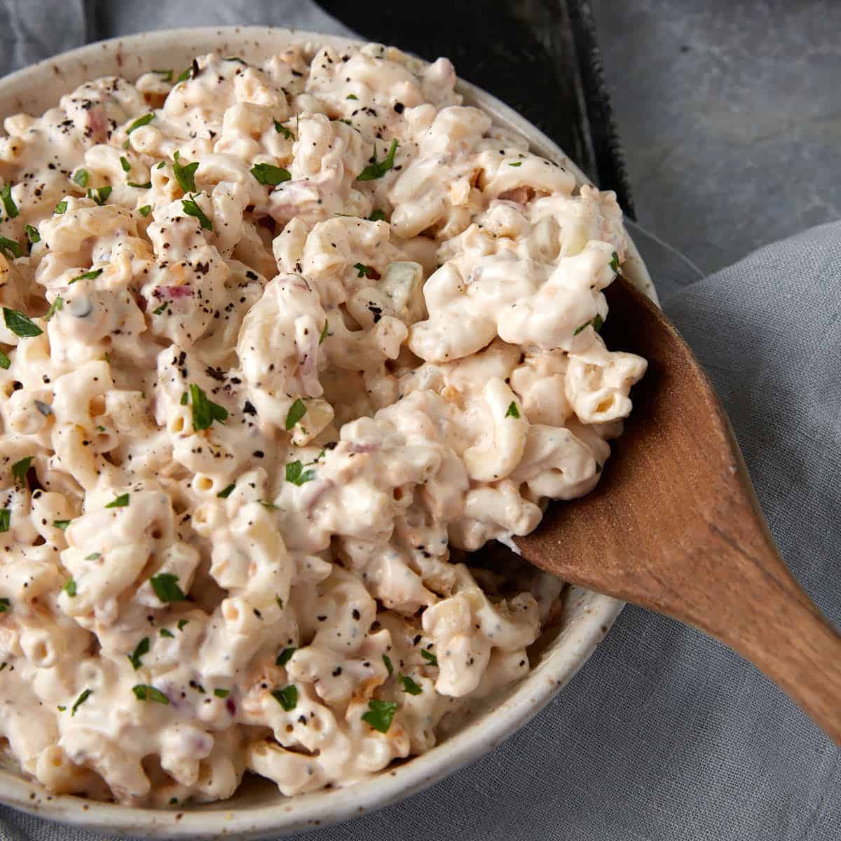 A wooden spoon with a serving of macaroni salad.