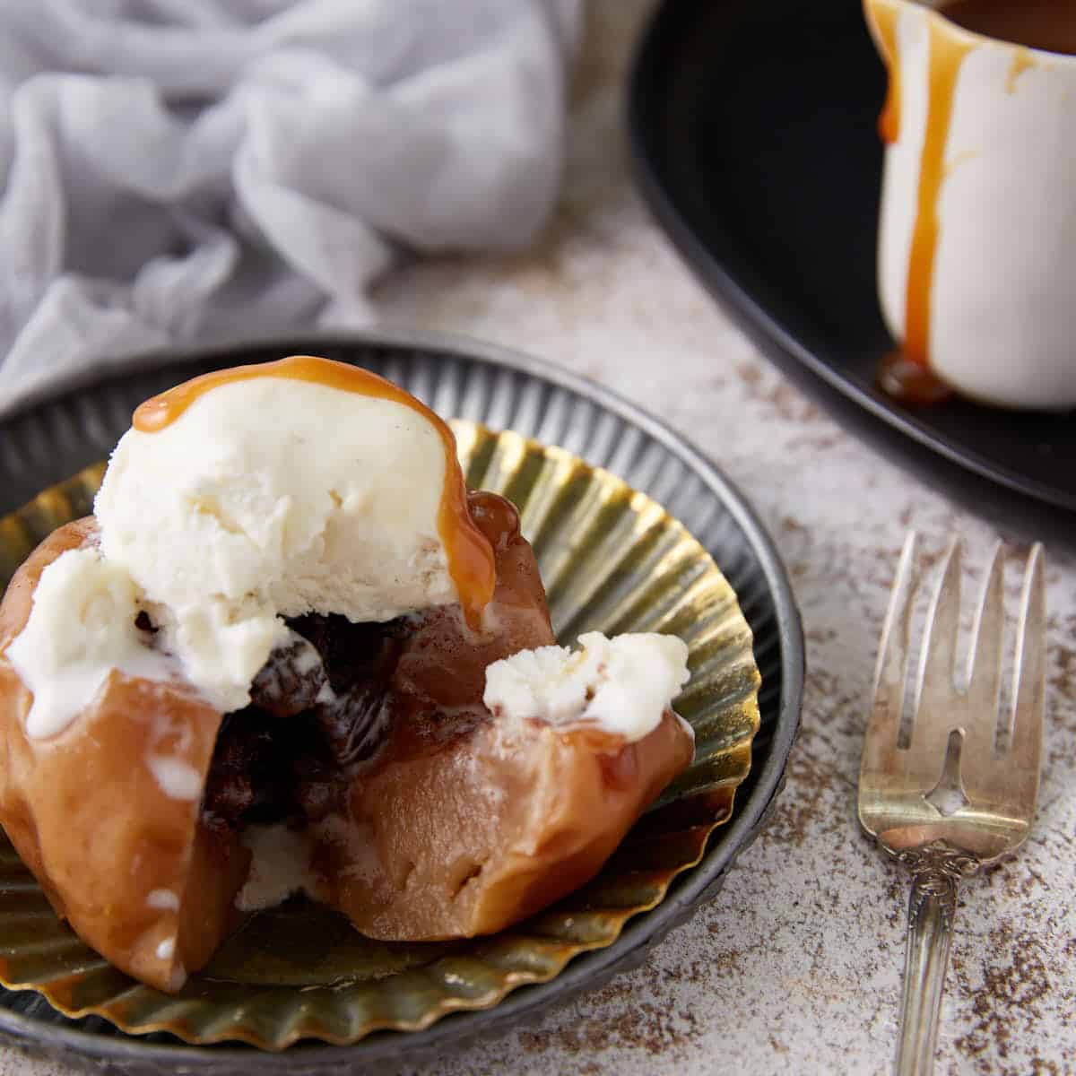 A single baked apple on a plate with a fork.