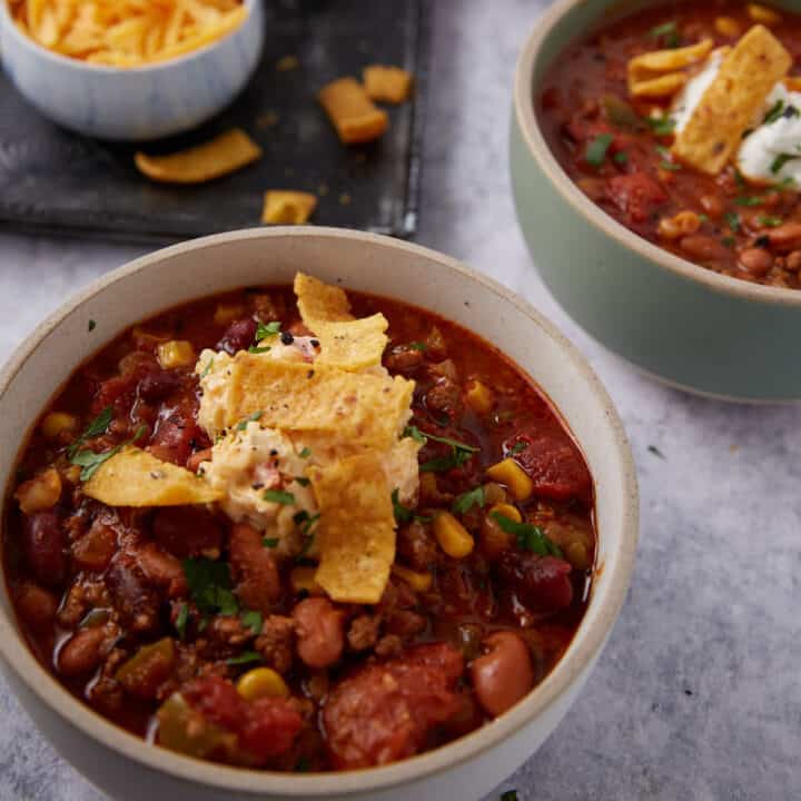Two bowls of taco soup with corn chips on top.