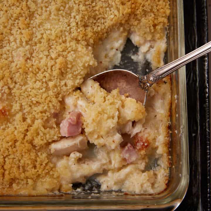 A spoon in a baking dish of chicken cordon bleu.