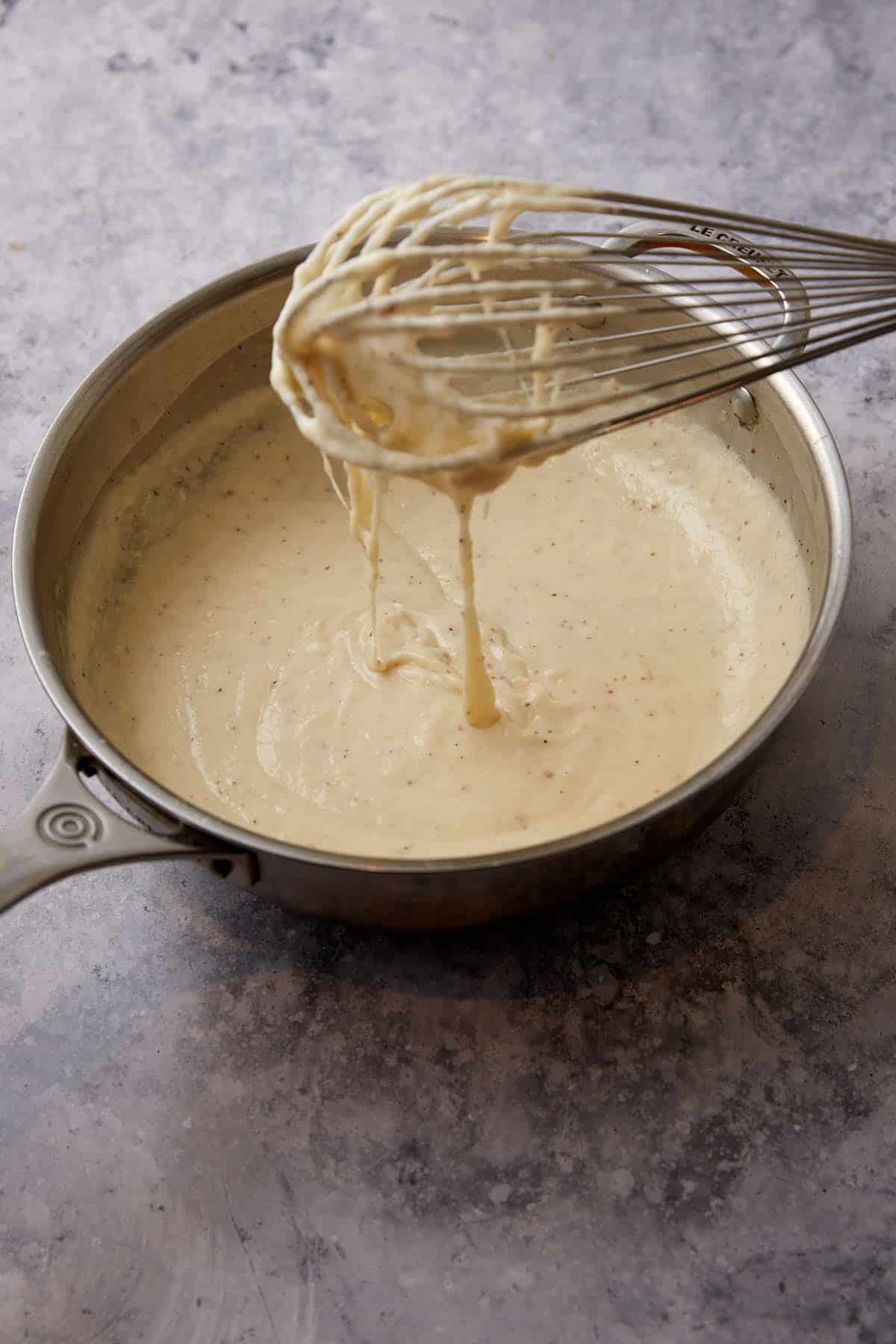 A cheese sauce in a saucepan.