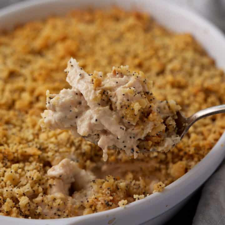 A serving spoon with a scoop of poppy seed chicken casserole.