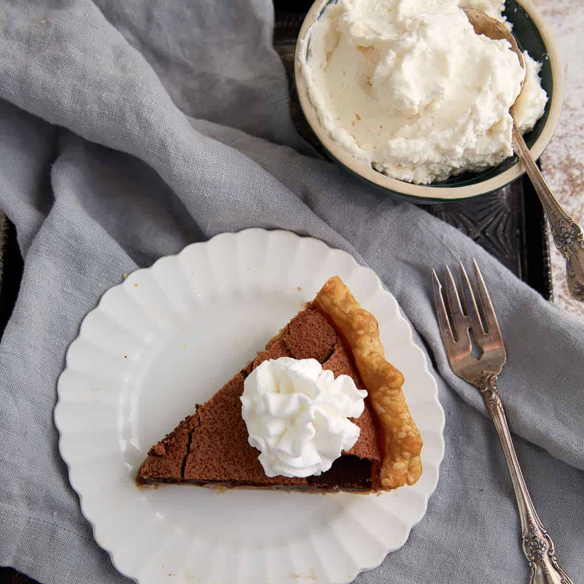 A single slice of chocolate chess pie with whipped cream on top.