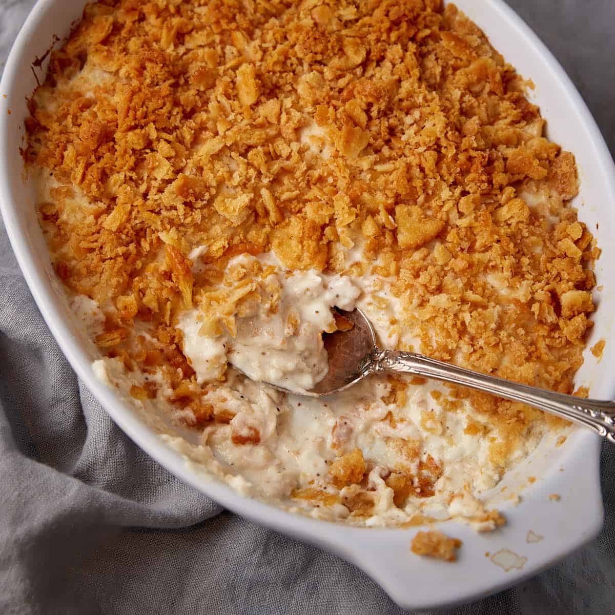 A serving spoon in a casserole dish of million dollar chicken.
