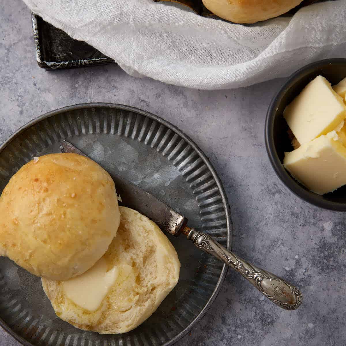 A potato roll cut in half with melted butter.