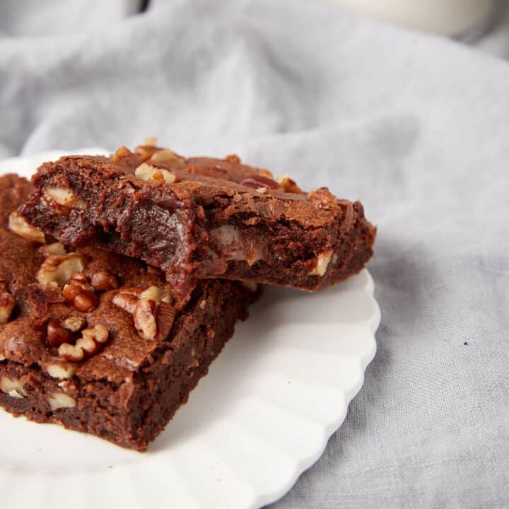 Two chocolate turtle brownies on a plate.