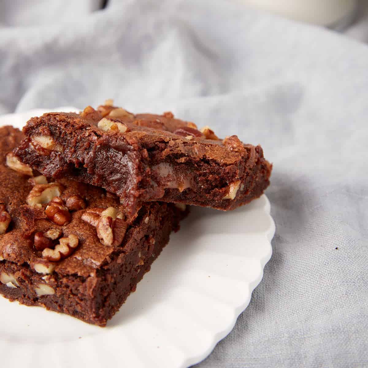Two chocolate turtle brownies on a plate.