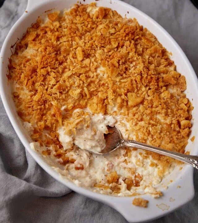 A serving spoon in a casserole dish of million dollar chicken.