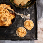 Two crackers with pimento cheese next to a bowl of cheese dip.
