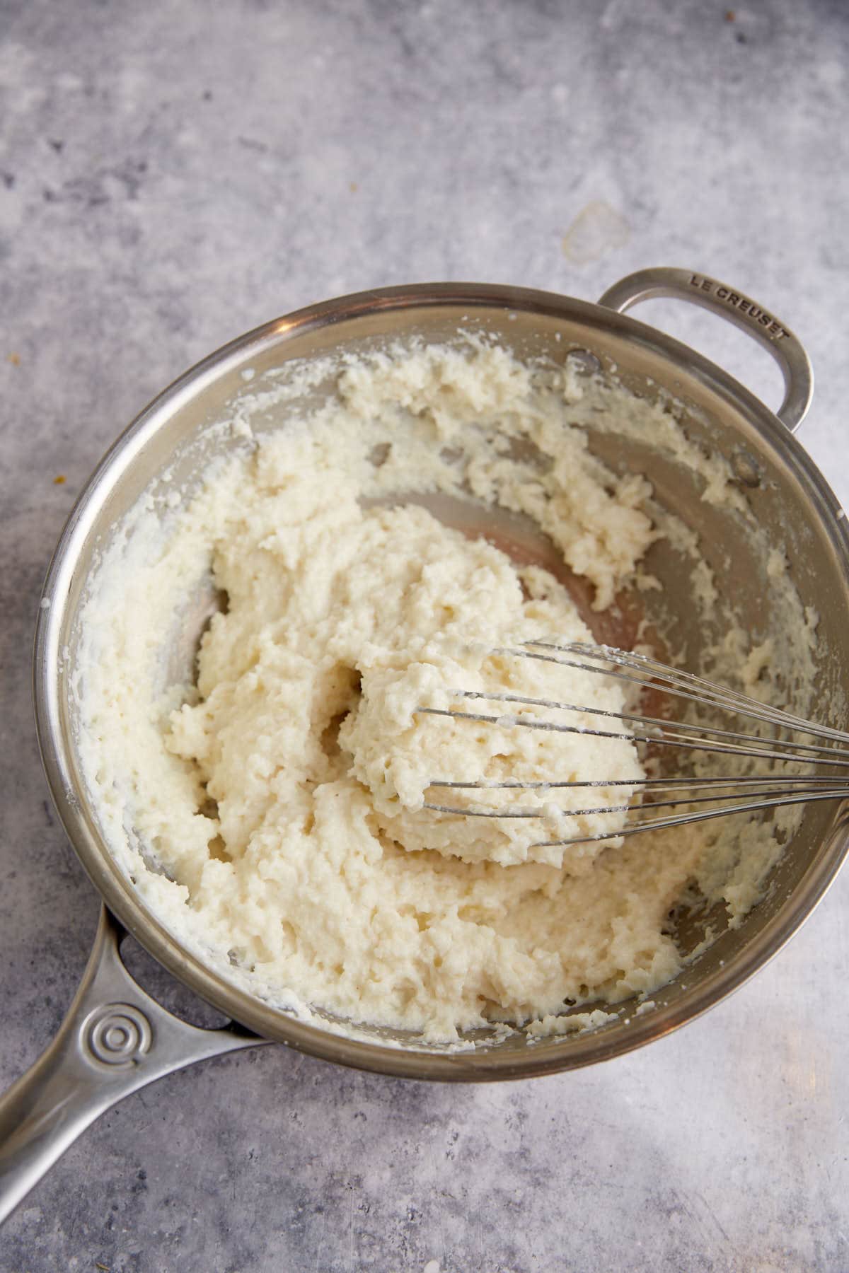 Cornmeal and milk in a skillet with a whisk.