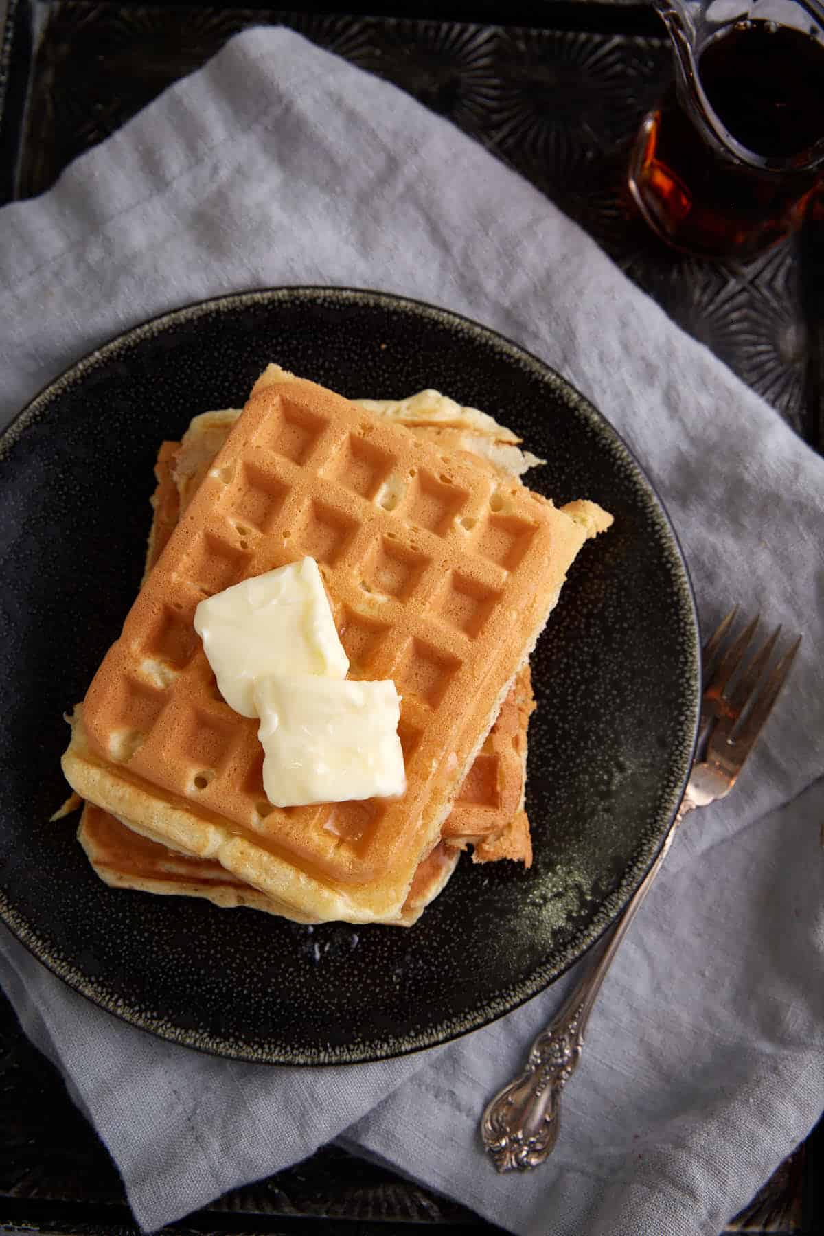 A stack of waffles with butter.