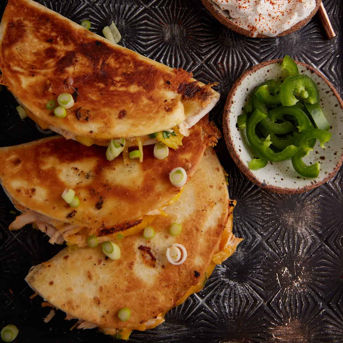 Three stuffed tortillas with toppings.