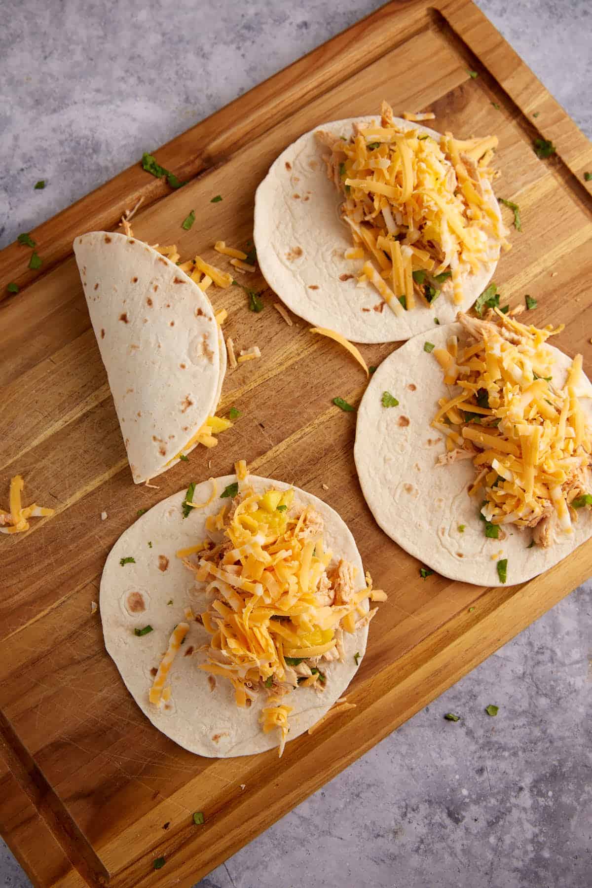 Cheese topped chicken quesadillas on a cutting board.