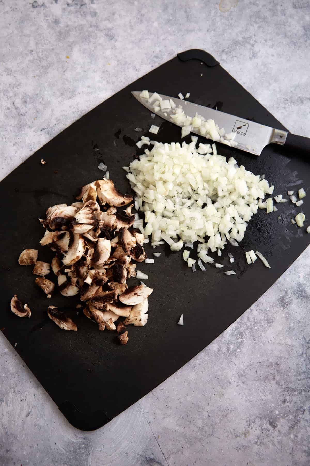 Chopped onions and mushrooms on a cutting board.