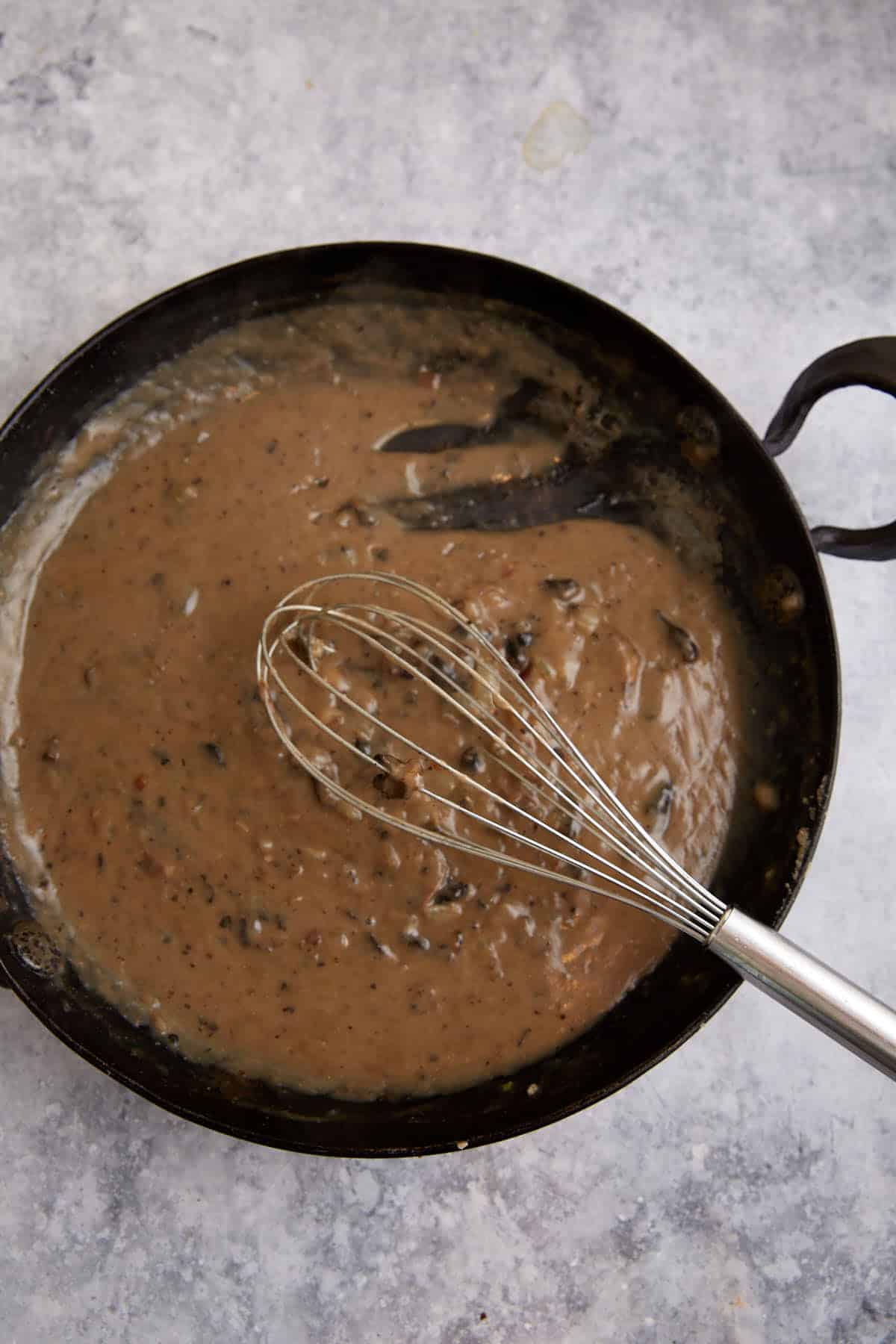 Chicken broth added to a mushroom base in a skillet.