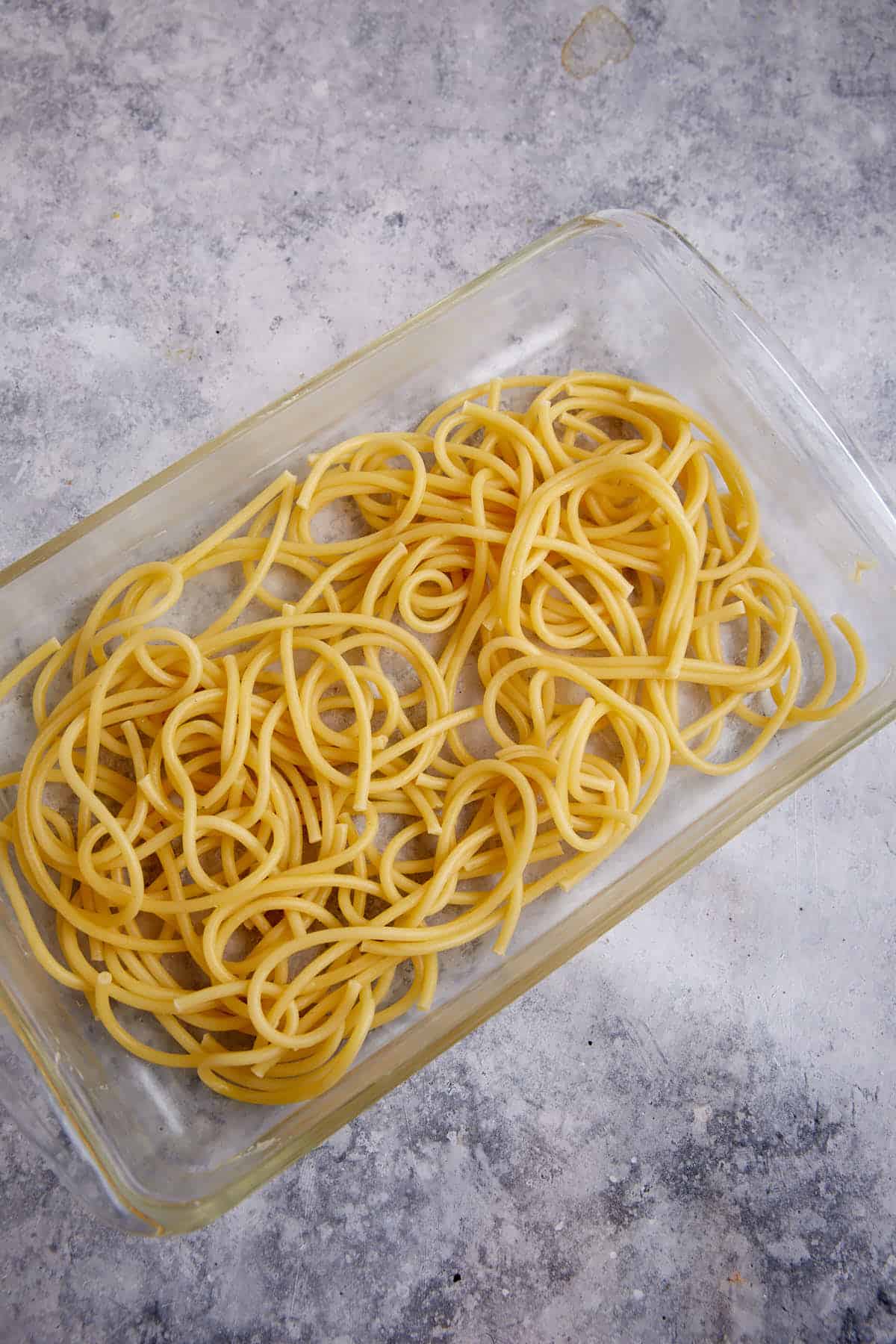 Cooked spaghetti noodles in the bottom of a casserole dish.