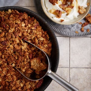 A bowl of spicy granola next to a bowl of yogurt.