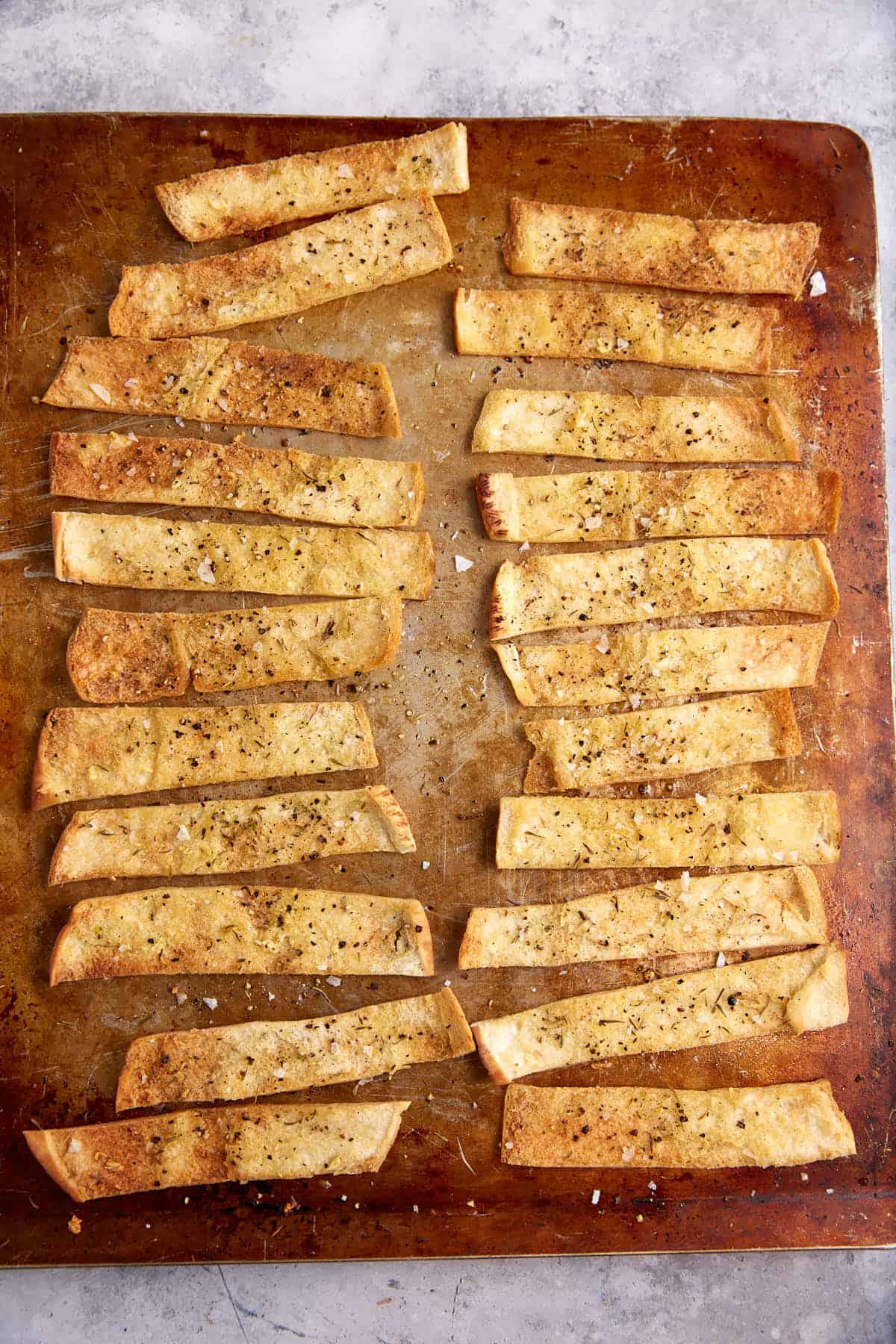 Baked pita chips on a cookie sheet.