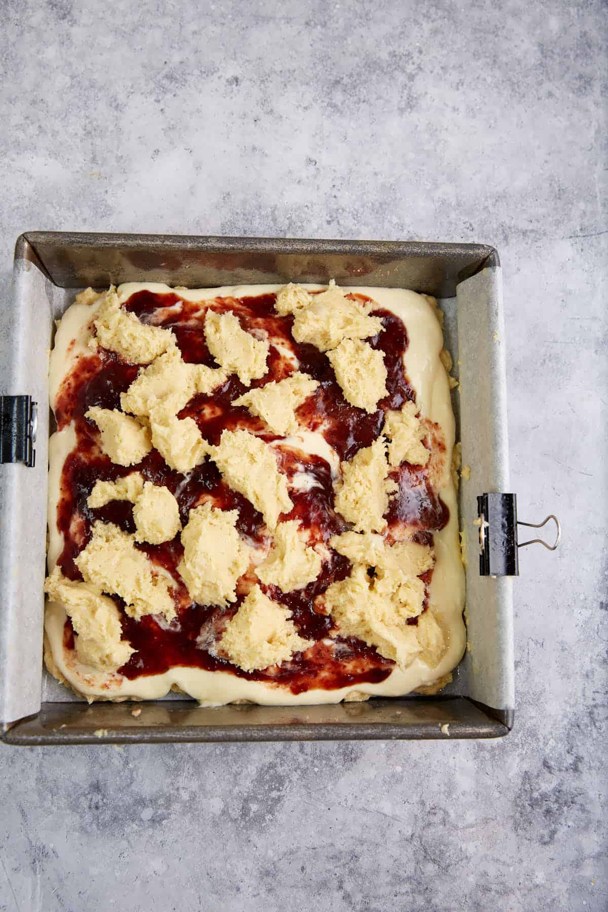 Dollops of cake batter on top of the jam layer.