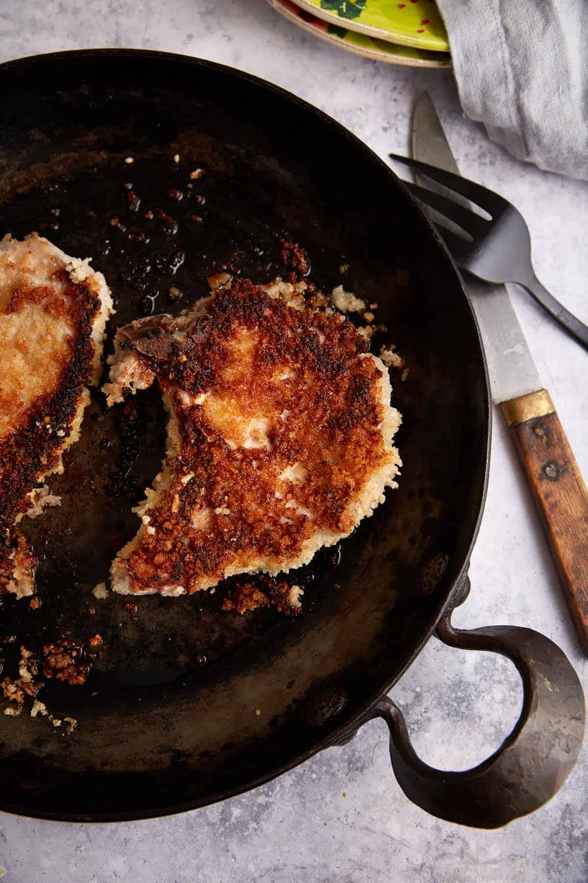 A skillet with breaded pork chops.