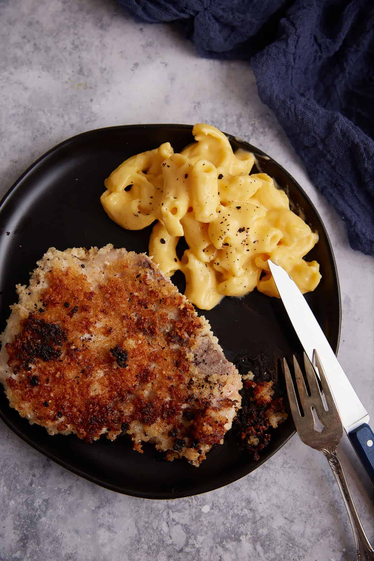  A breaded pork chop on a plate with macaroni and cheese.