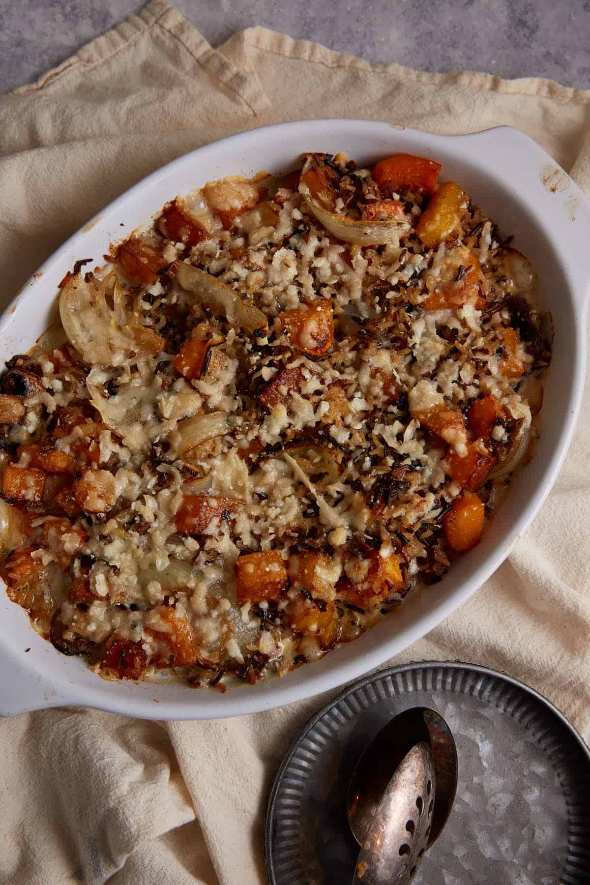 A baked wild rice casserole next to a serving spoon.