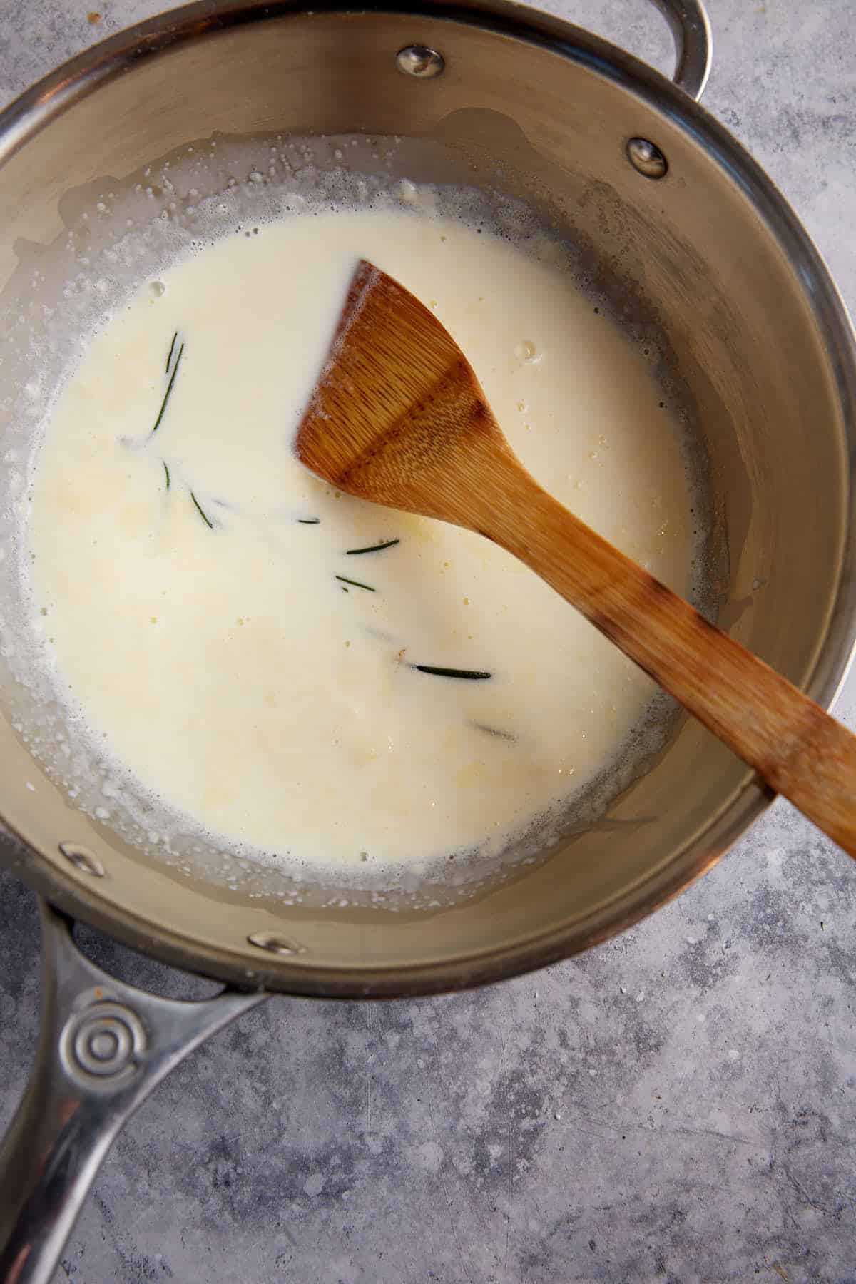 Cream with rosemary in a saucepan.