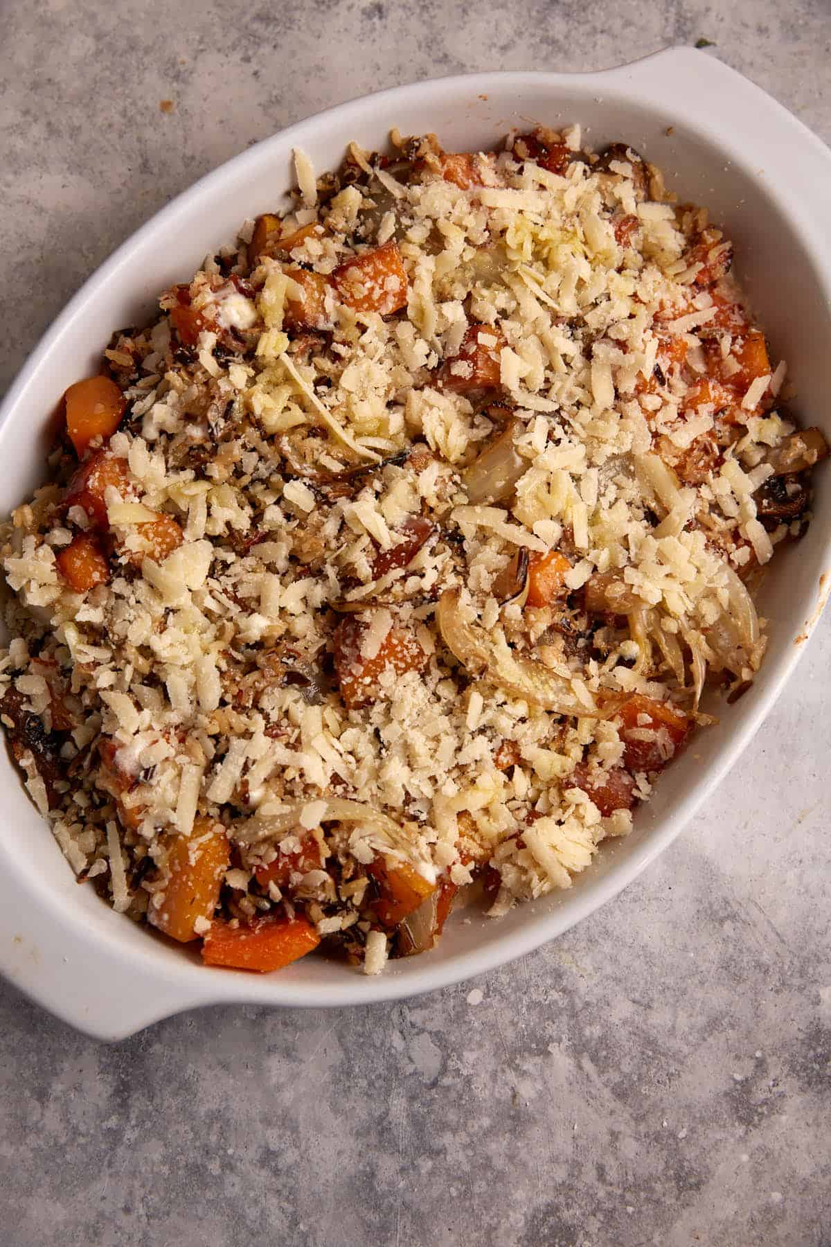 A baking dish with butternut squash casserole covered with cheese.