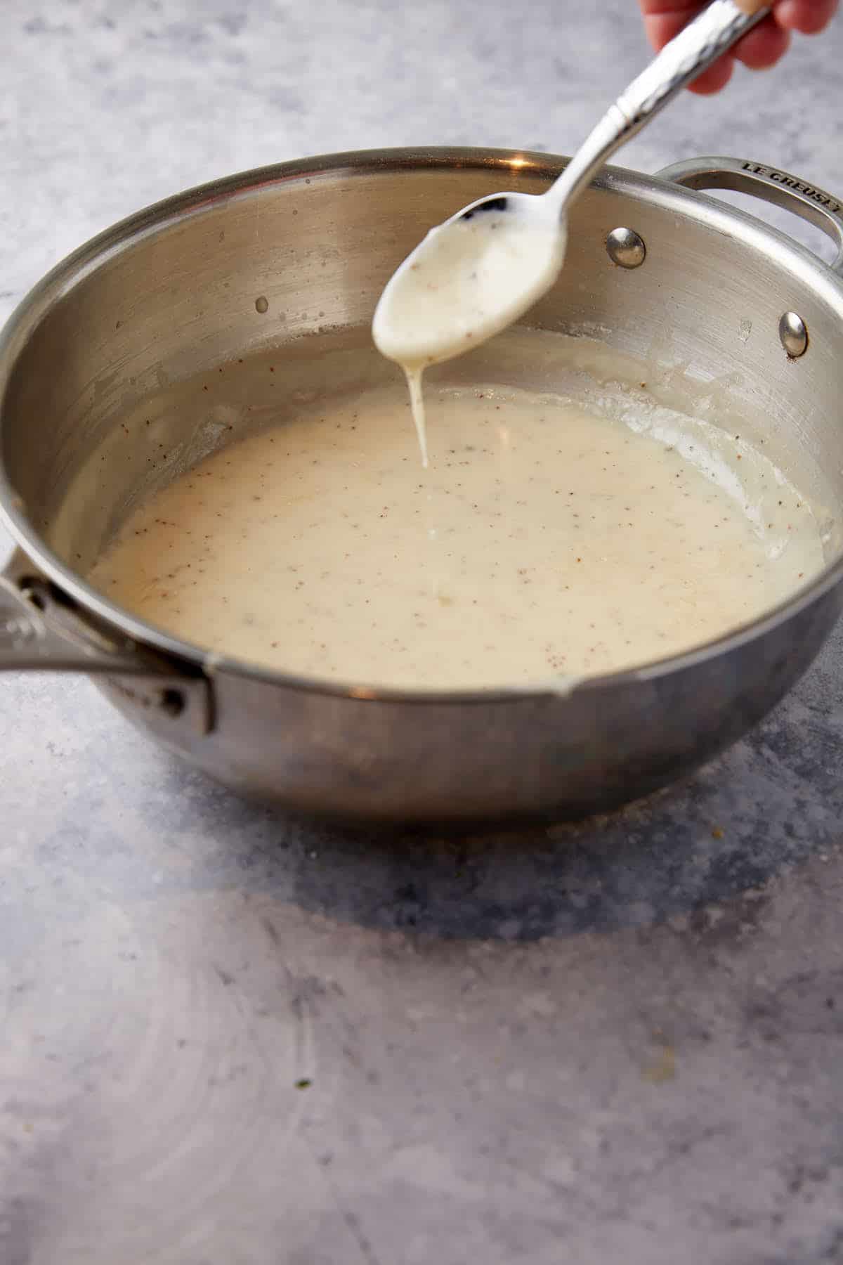 A spoon stirring a saucepan of soup.