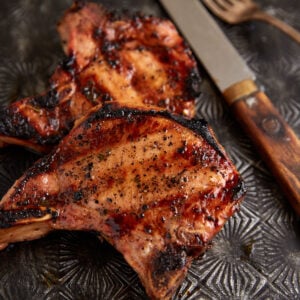 Bone in pork chops next to a knife.
