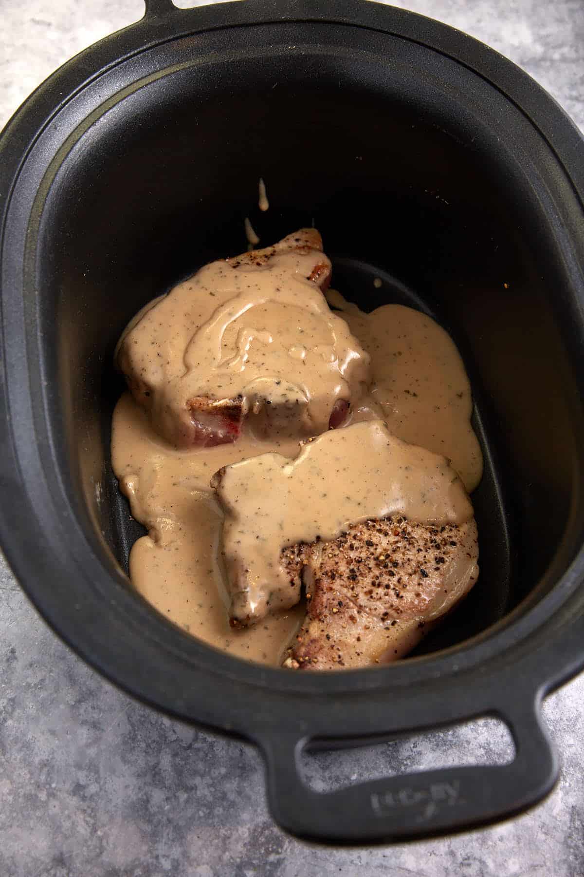 Pork chops in a slow cooker covered with Ranch gravy.