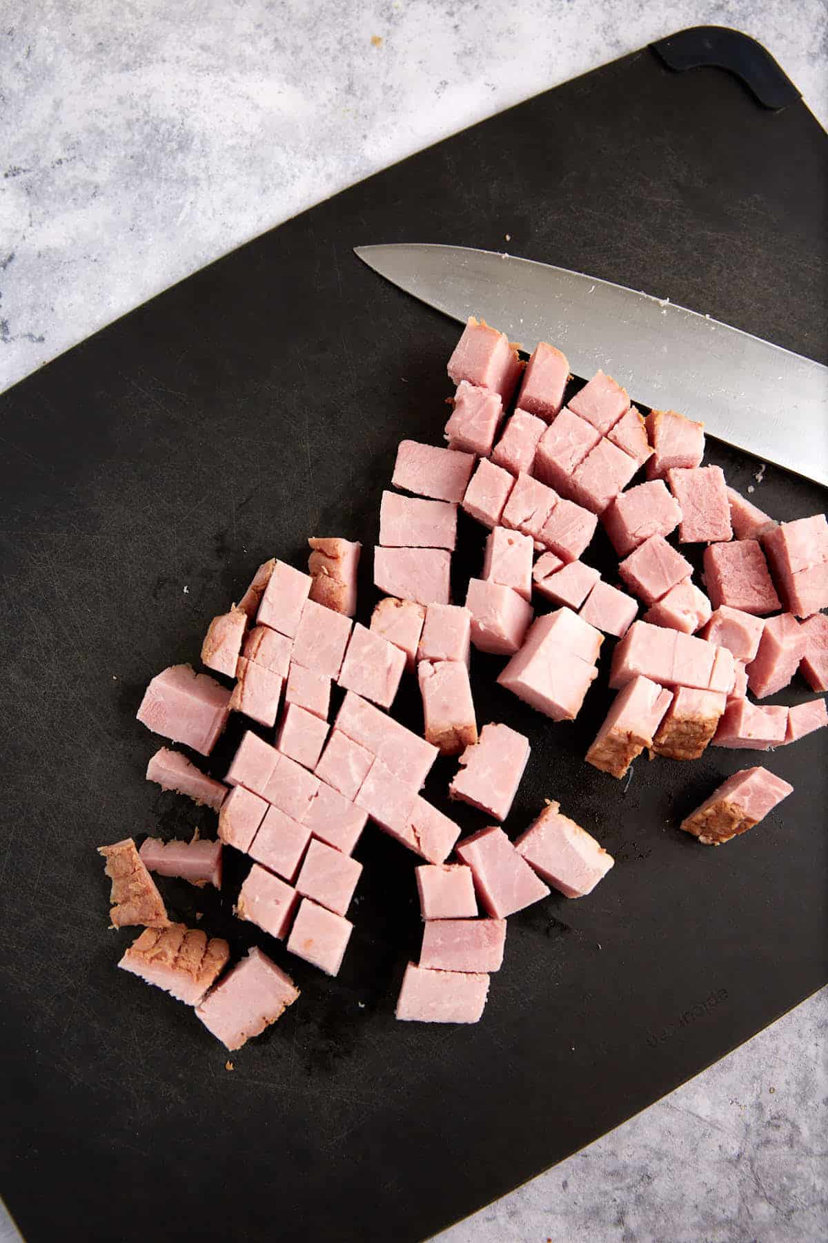 Cooked ham cut into cubes on a cutting board.