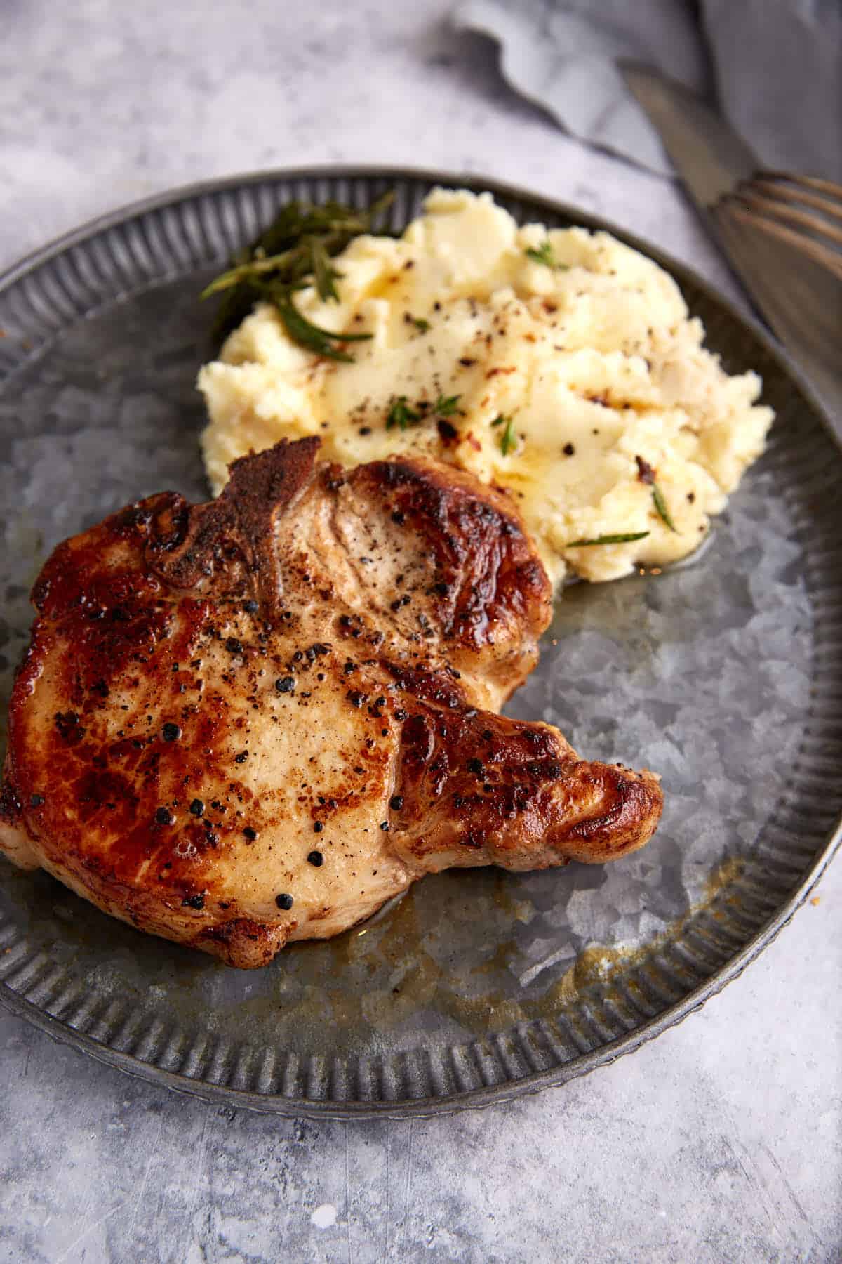A pork chop next to mashed potatoes.