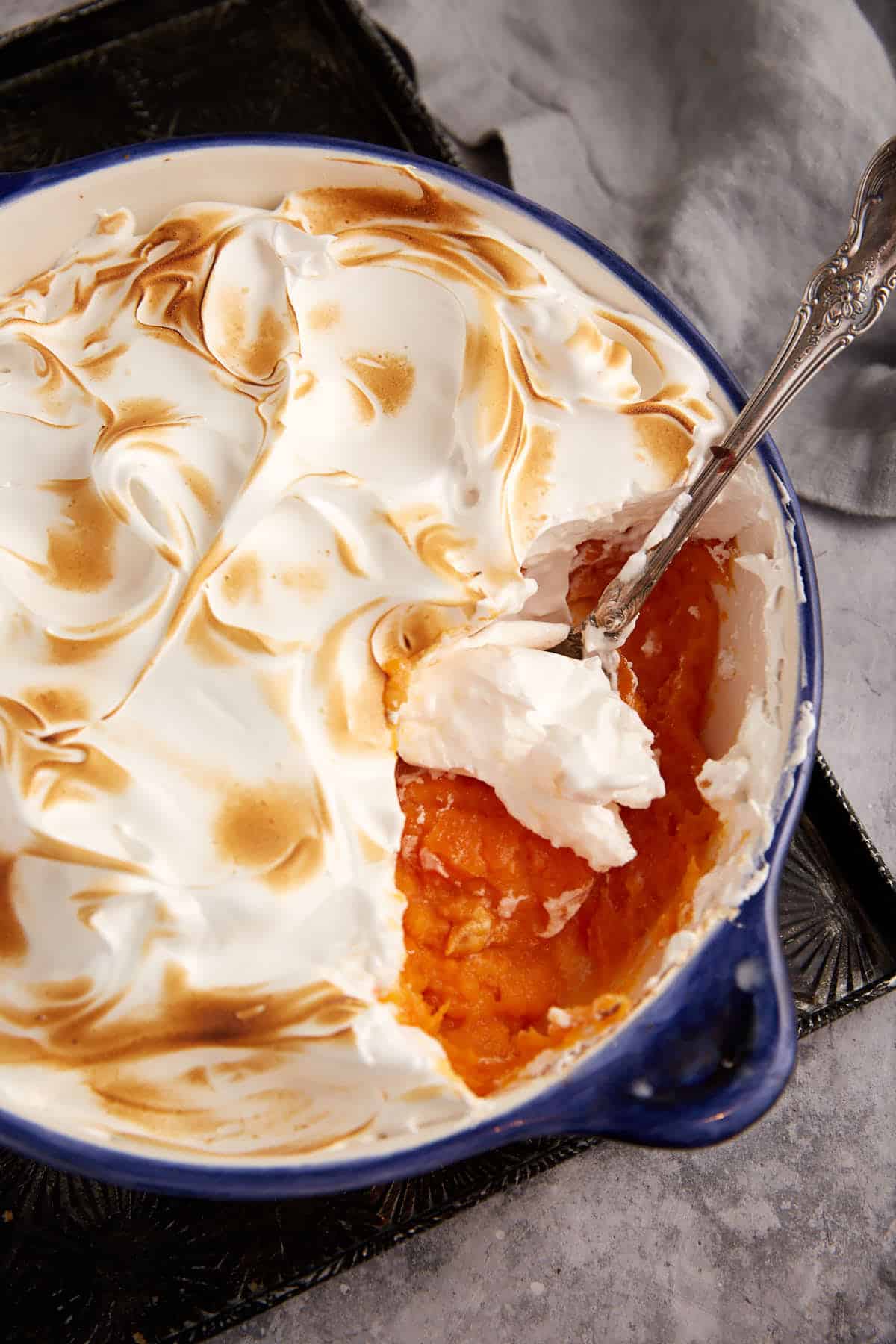 A spoon full of marshmallow topped sweet potato casserole.