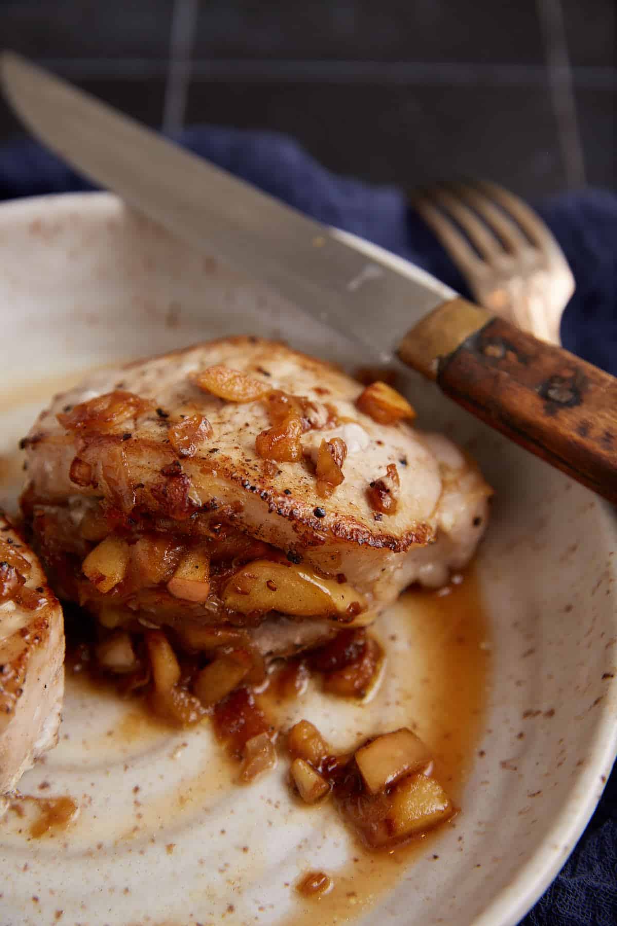 A stuffed pork chop next to a knife and fork.