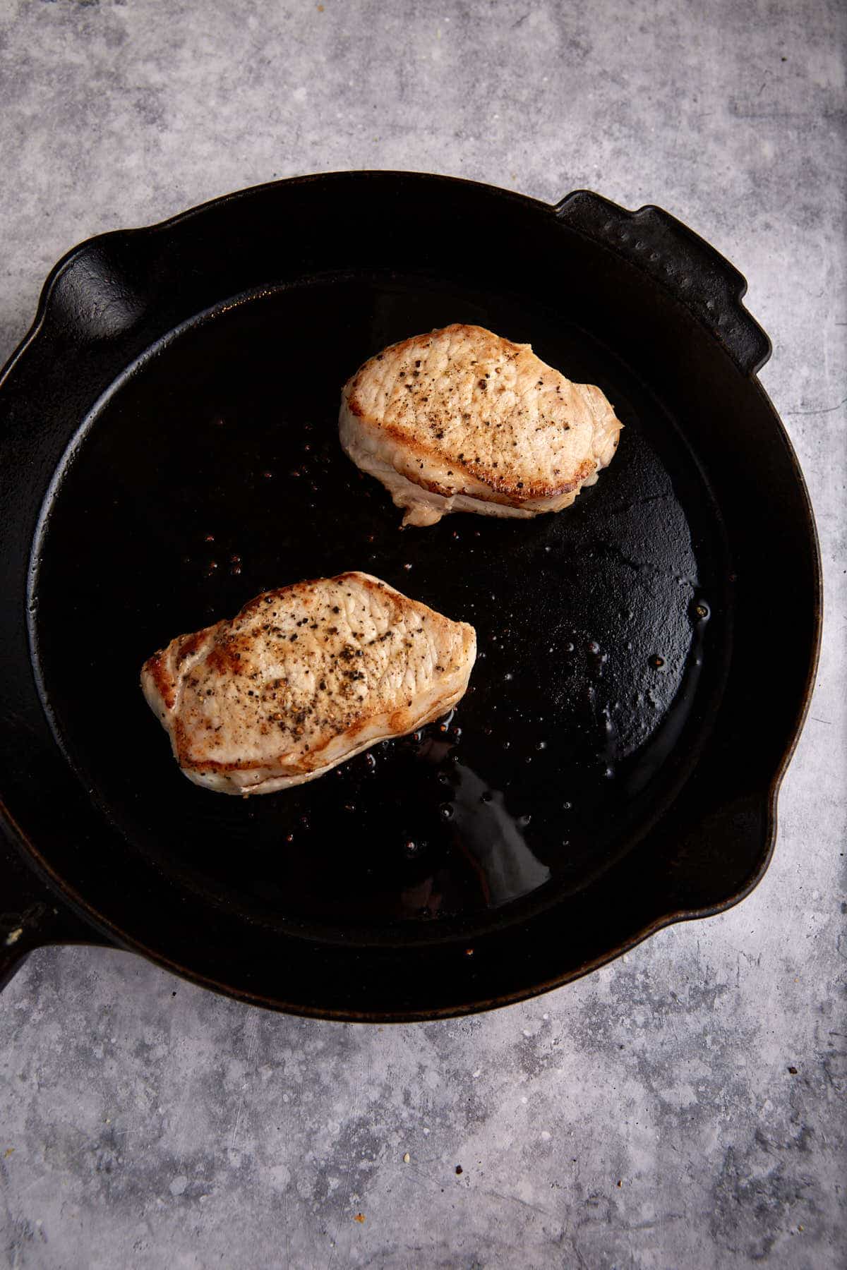 Seared pork chops in a skillet.