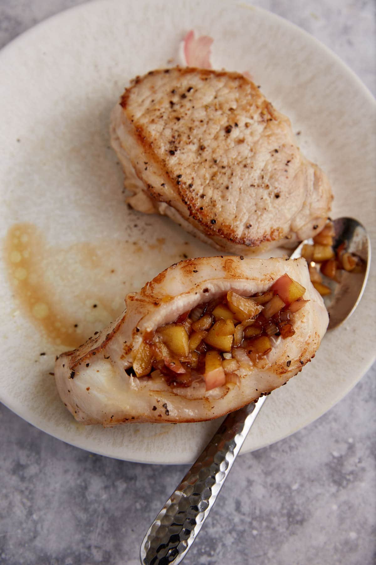 Pork chops being stuffed with apples.