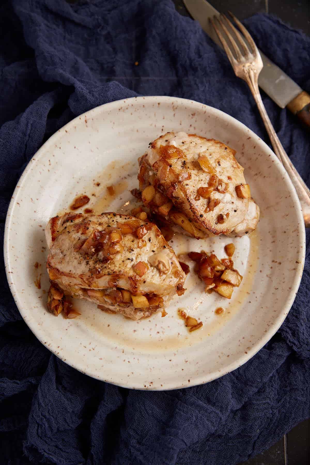 Two apple stuffed pork chops on a plate. 