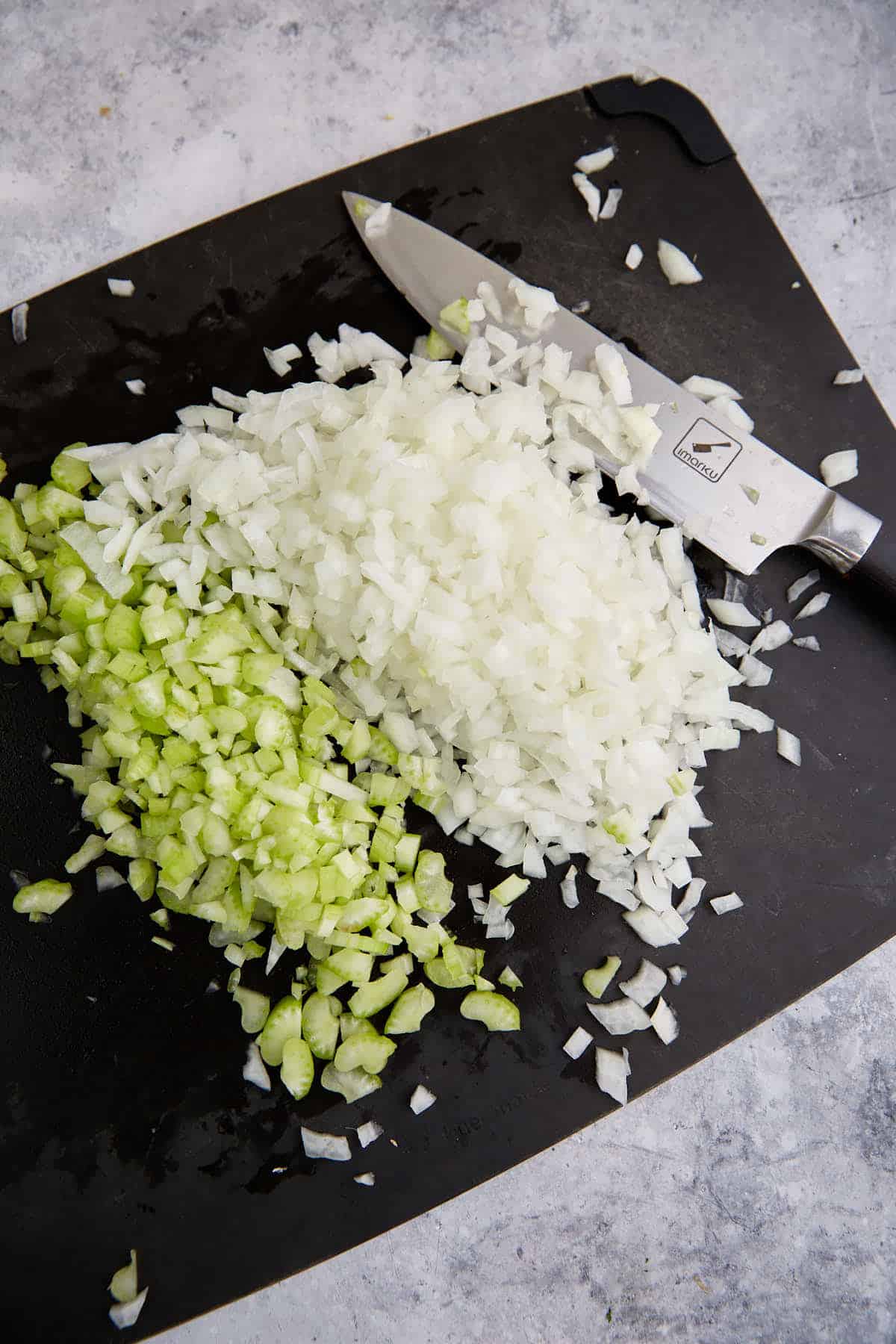 Chopped celery and onions on a cutting board.