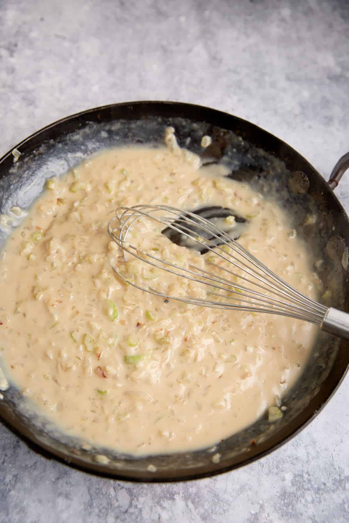 A white sauce thickened in a skillet.